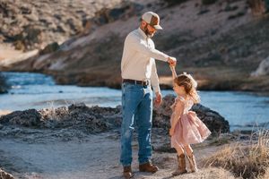 Family enjoying a playful moment together near a rocky coastline at sunset.