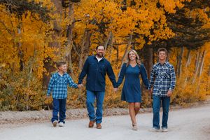 Family walking together on path surrounded by vibrant golden fall trees.