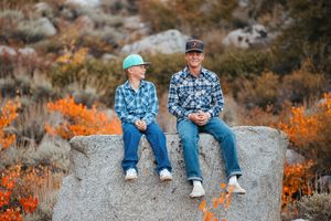 Group sitting casually on rocks with autumn colors in background.