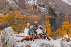 Family photo session on rocky terrain with golden fall foliage in background.