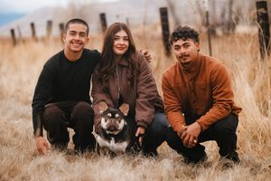 Group portrait in casual earth tones against autumn grass background.
