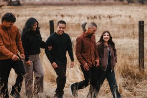 A group walks together through a golden autumn field at sunset.