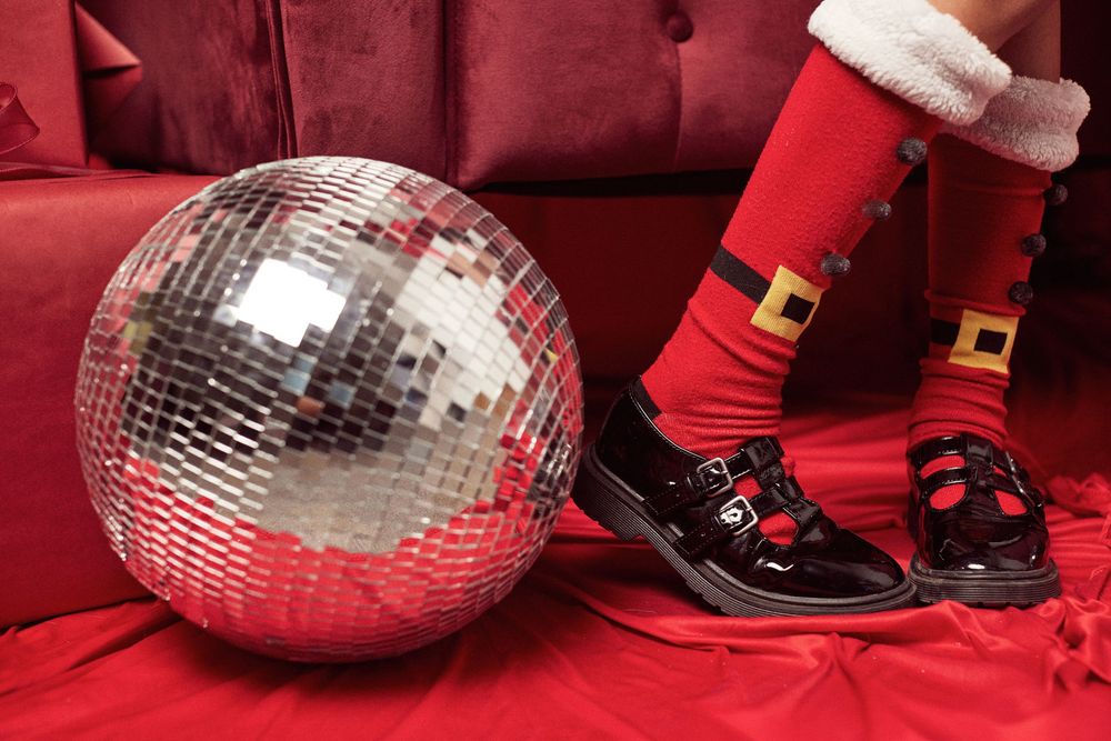 Silver disco balls and black patent shoes with white trim in red holiday setting.