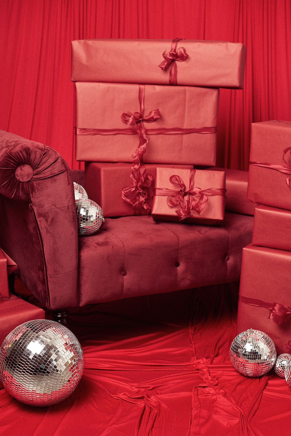 Burgundy couch with red wrapped presents and silver disco balls in monochromatic setting.