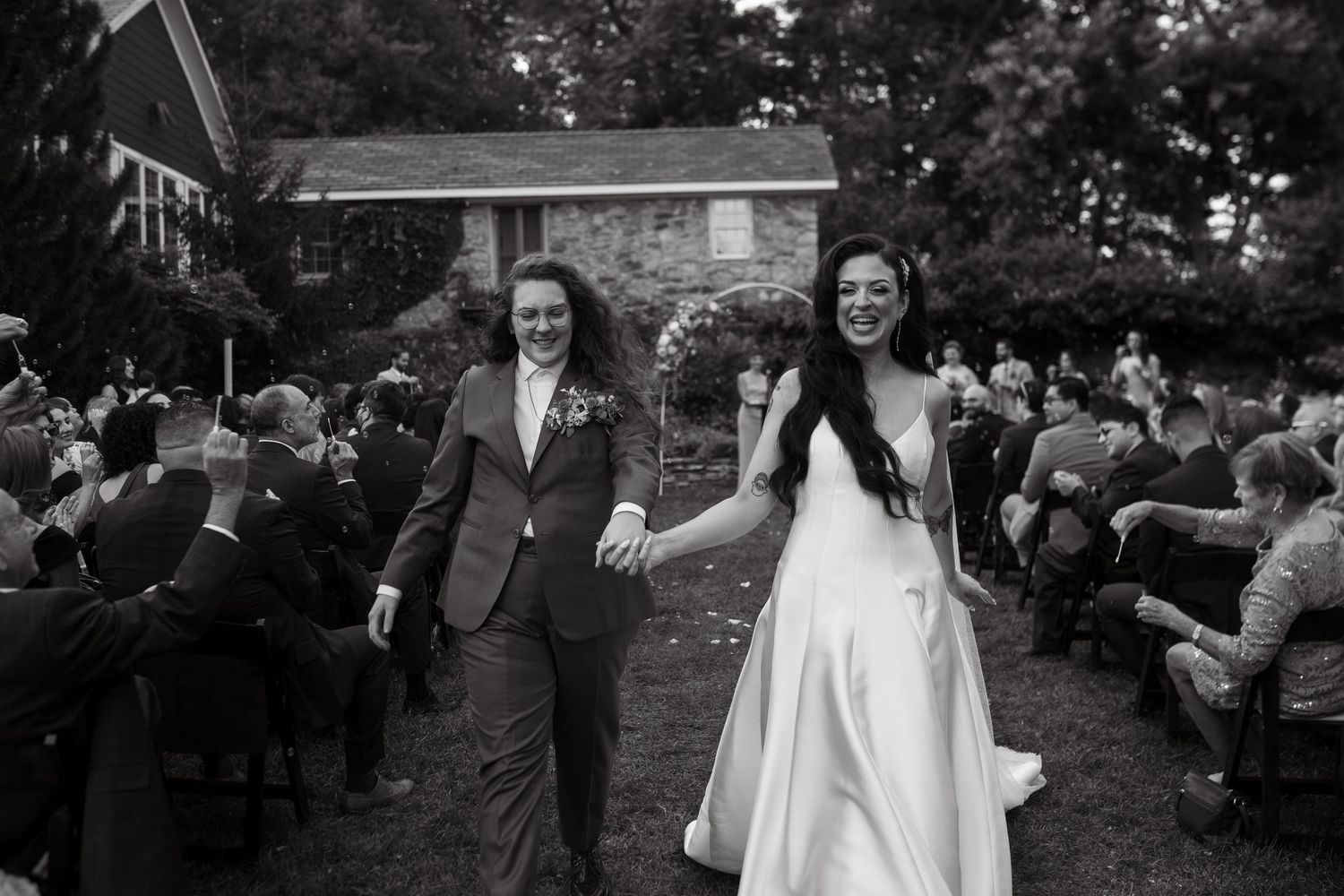 A collection of black and white wedding photos showing moments between a couple and guests during an outdoor ceremony.
