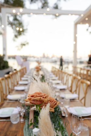Elegant outdoor wedding reception table setup with wooden chairs and string lights creating a romantic atmosphere.