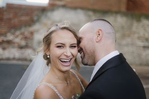 A happy couple shares joyful moments together during their wedding photo session in a rustic outdoor setting.