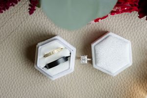 Elegant engagement rings and wedding bands displayed in white hexagonal jewelry boxes.