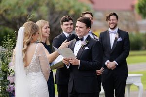 Wedding party members share joyful laughter during an outdoor ceremony moment.