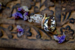 A delicate purple flower blossom rests on rustic wooden boards with soft natural lighting.