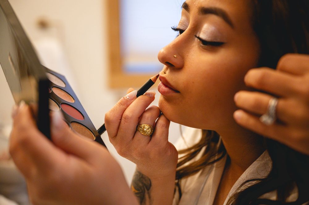 Professional makeup artist applying cosmetics to model's face during beauty session at studio.
