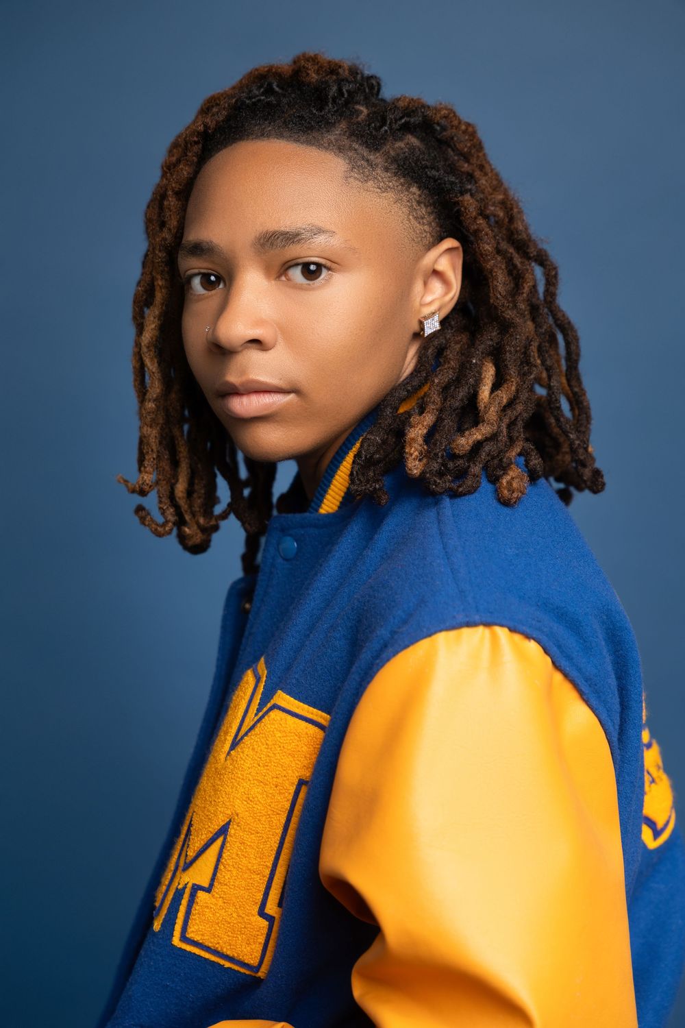 Shank Henry Media series of senior profile photos against a blue background showing curly hair and a blue and gold varsity jacket.