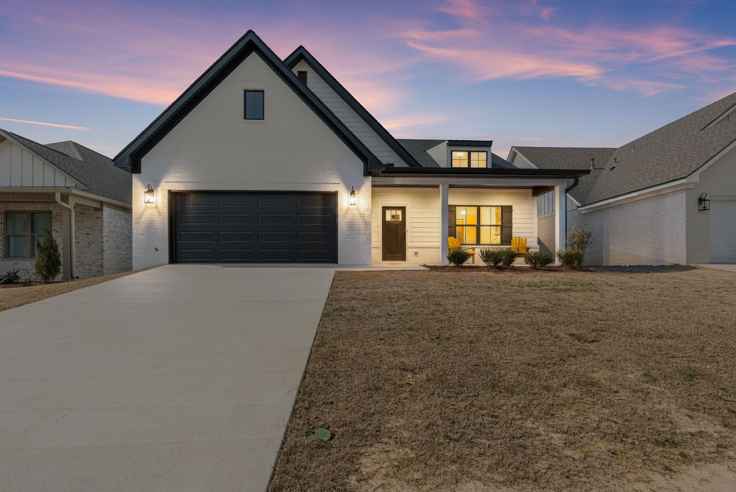 Modern house exterior at dusk with warm glowing windows.