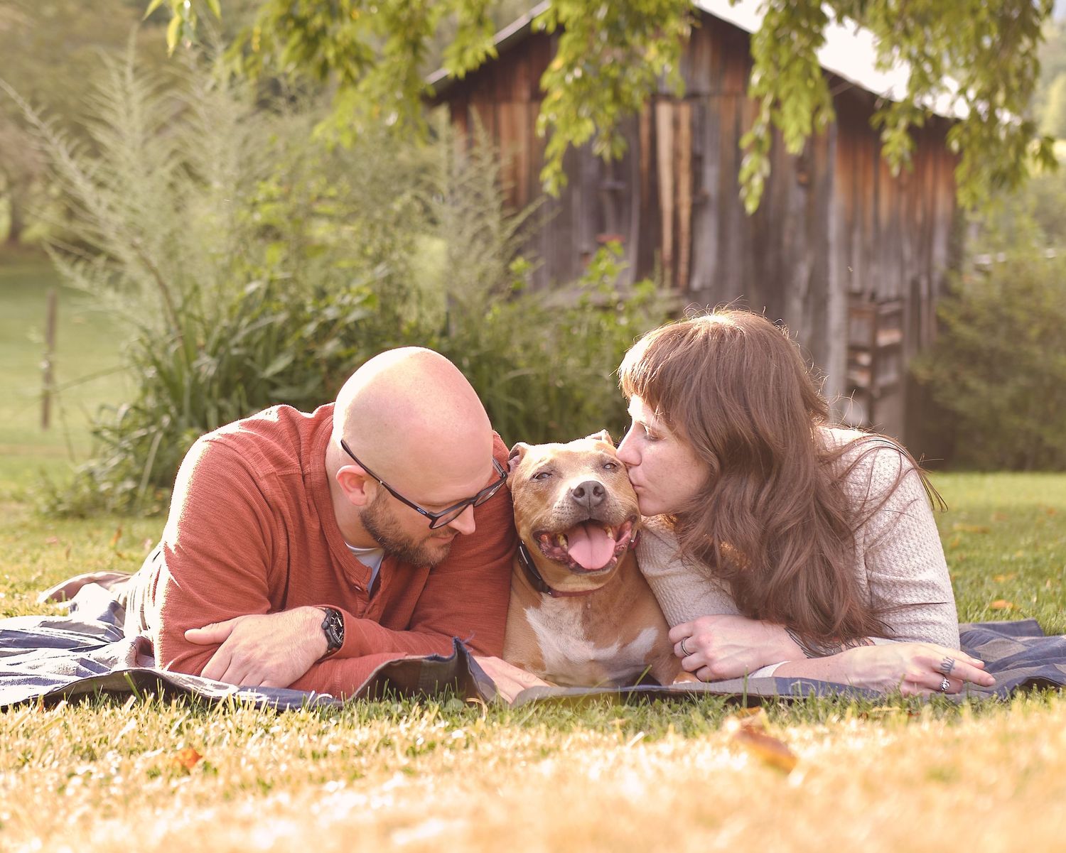 A couple lying together on golden grass during sunset creating a romantic outdoor scene.