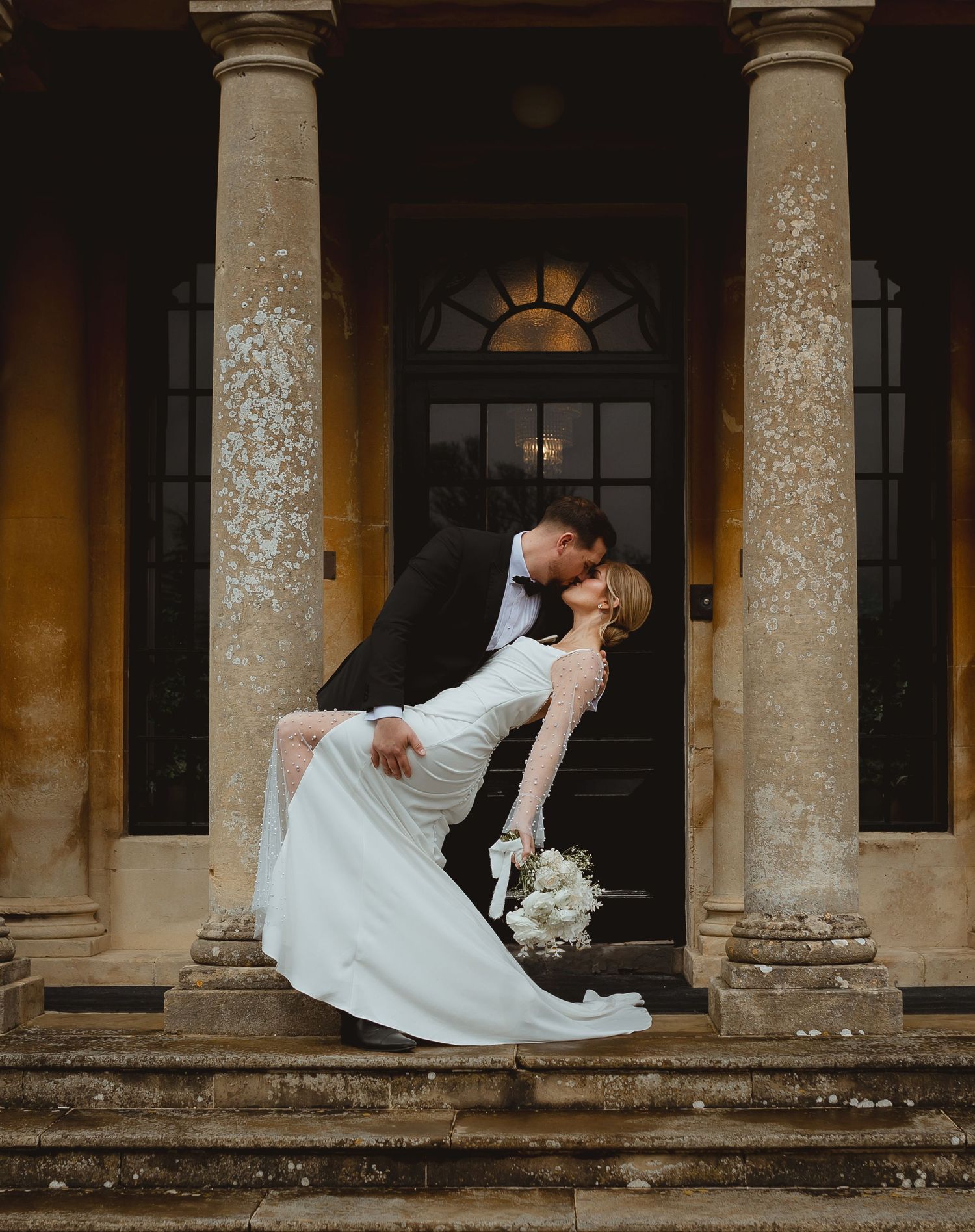 A couple in wedding attire sharing romantic poses against classical stone columns in a dramatic sequence.