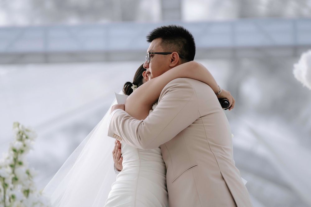 Emotional bride and groom sharing heartfelt hug during outdoor wedding ceremony.