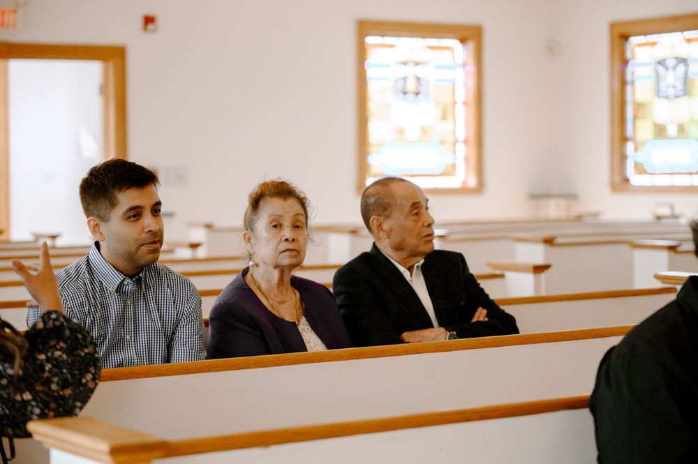 People sitting attentively in wooden church pews during a service.