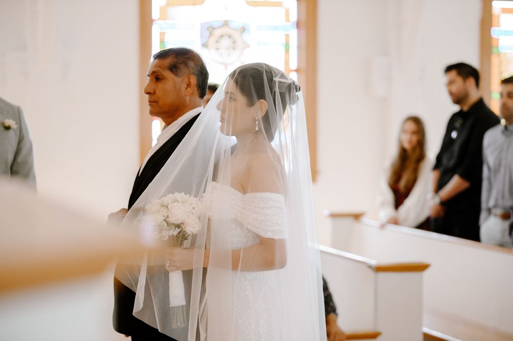 Bride and groom share an intimate first look moment in a bright white room.