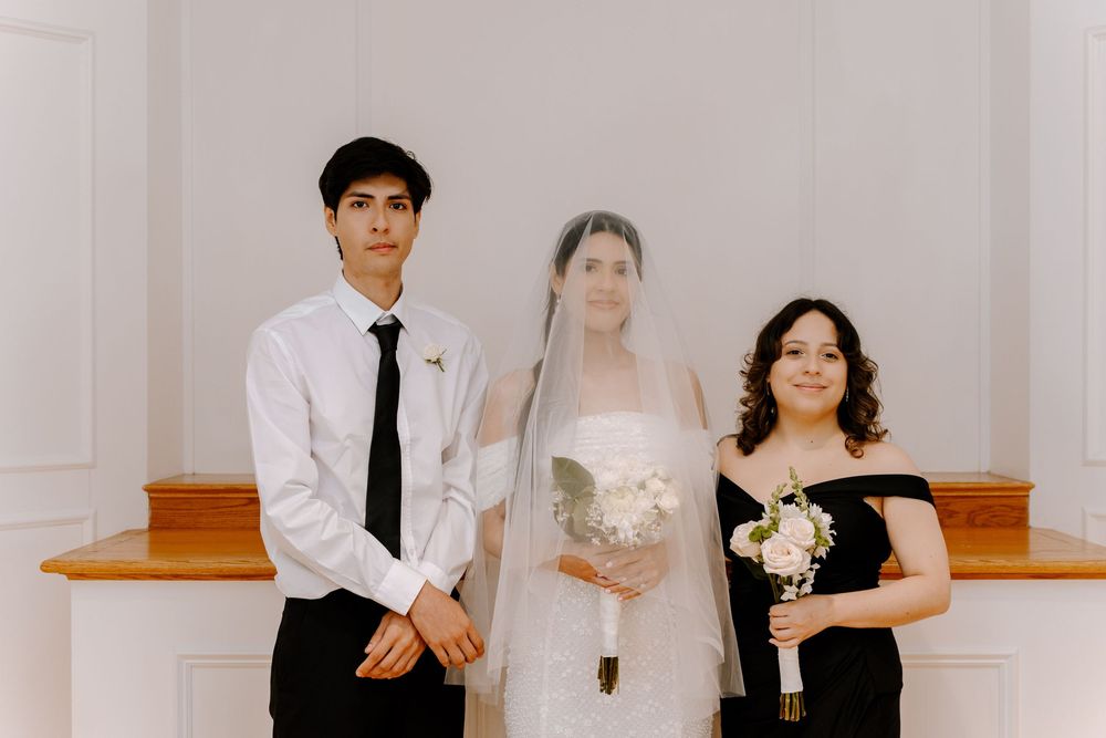 Wedding couple poses elegantly in a minimalist white interior space.