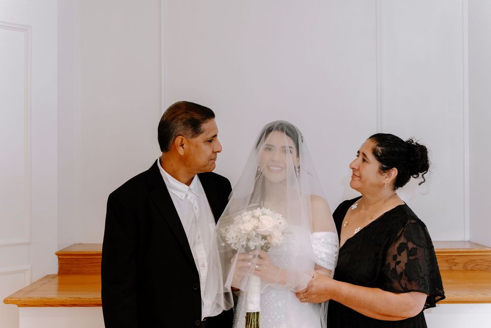 Wedding ceremony preparations in a bright white hall with wooden floors.