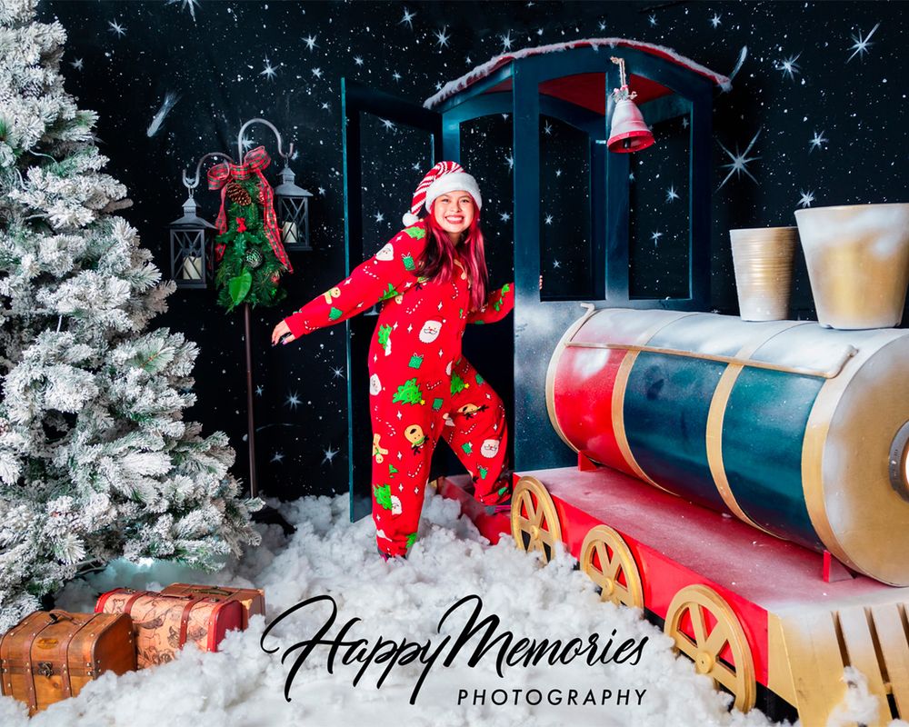 Holiday scene with toy train, wrapped presents, and falling snow against dark backdrop.