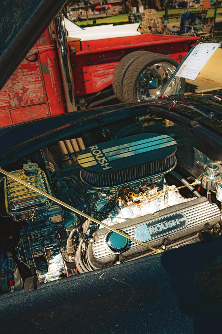 Four close-up views of a custom car engine bay showing chrome and blue painted valve covers and air intake components.