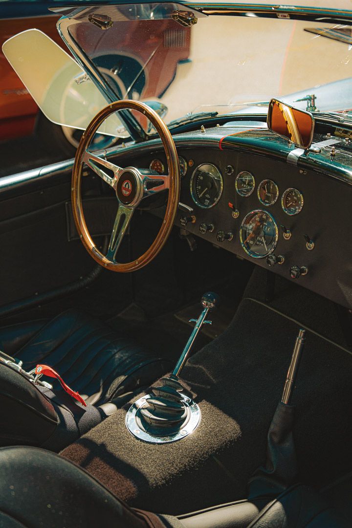 Vintage car dashboard with wooden steering wheel and classic gauges showing interior details of a classic automobile.