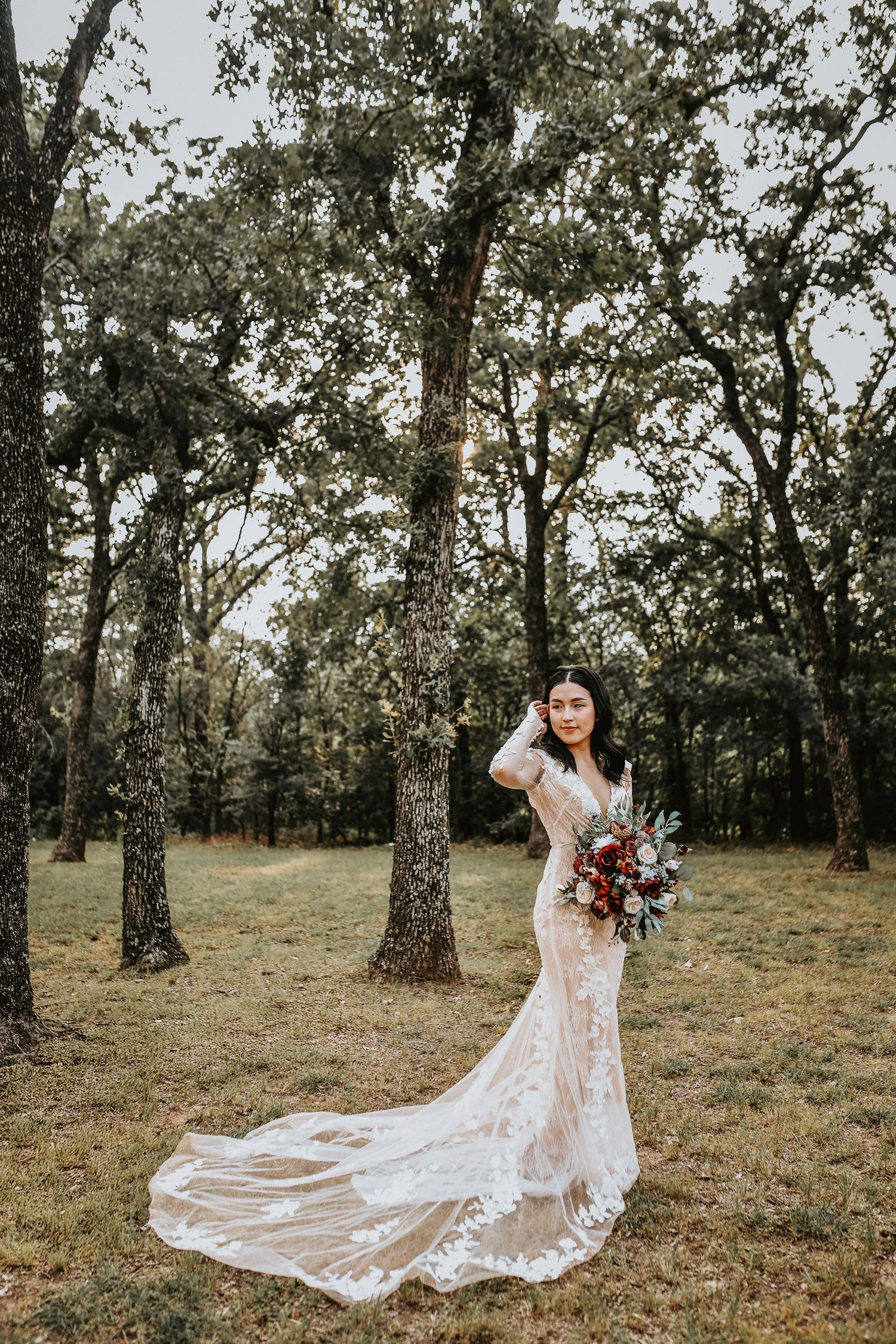 Bride in lace gown holding burgundy flowers at Bentley Station in Lake Dallas