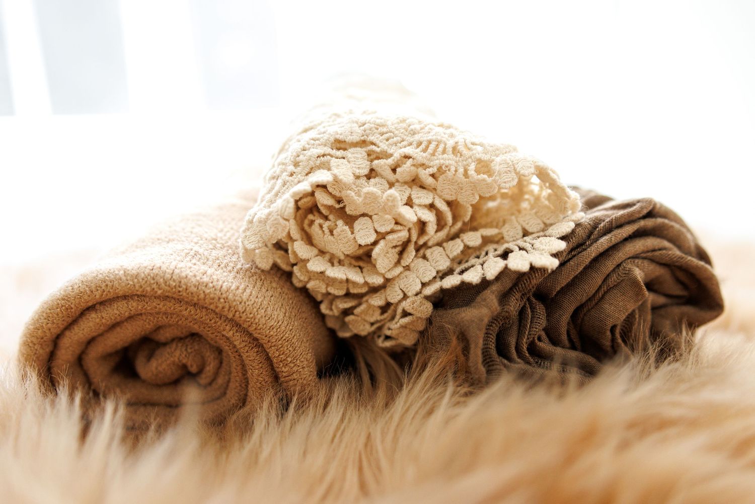 A small white teddy bear rests next to a business card on delicate lace fabric.