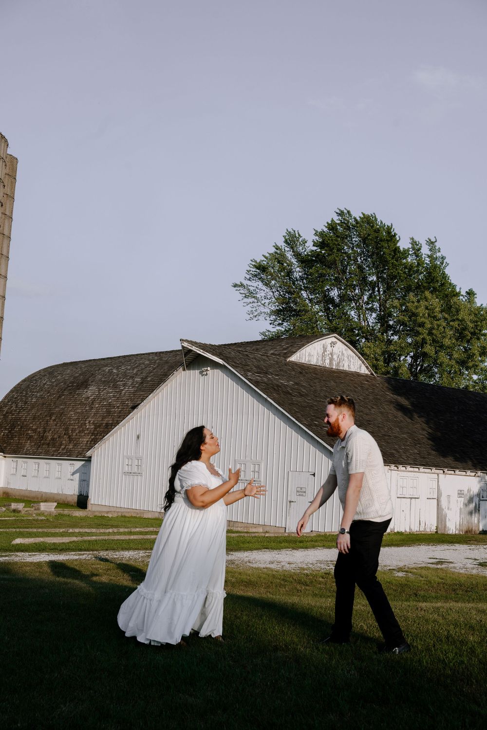 Dancing couple perform dramatic poses against a white barn backdrop in a rural setting.