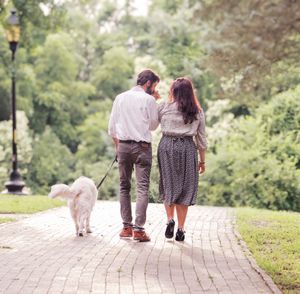A couple walks together on a brick path through a lush garden setting.