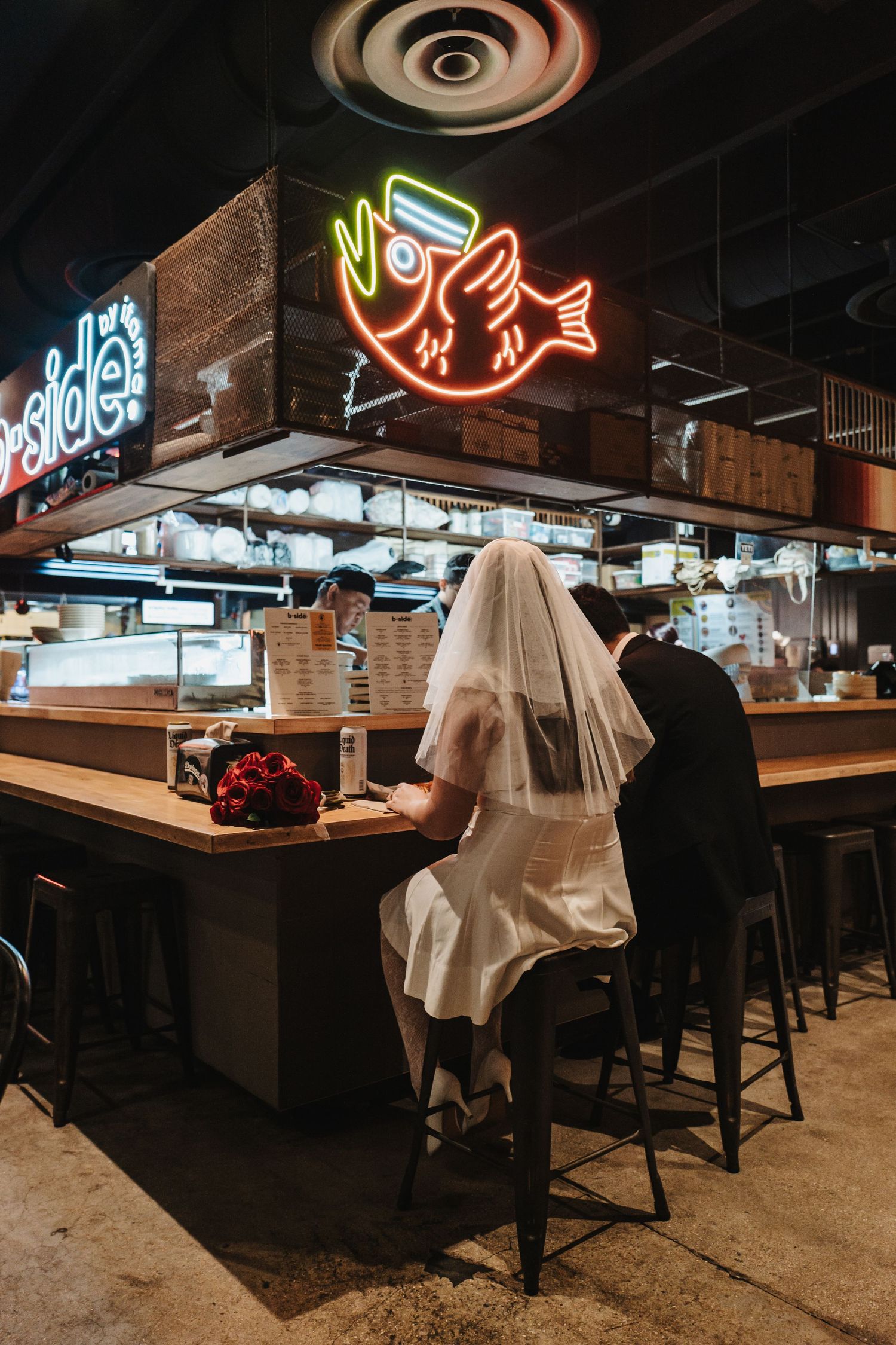 Dimly lit modern restaurant interior with neon fish signs glowing on the wall and bar seating along a counter.