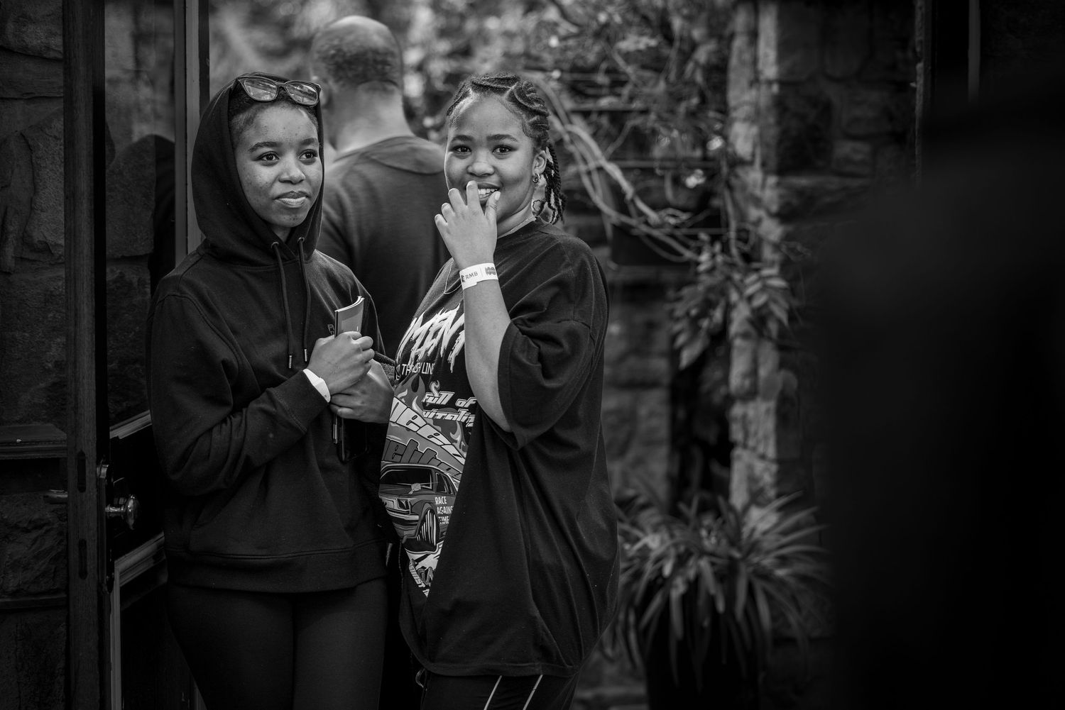 Black and white candid shot of two friends in dark hoodies sharing a laugh outdoors.