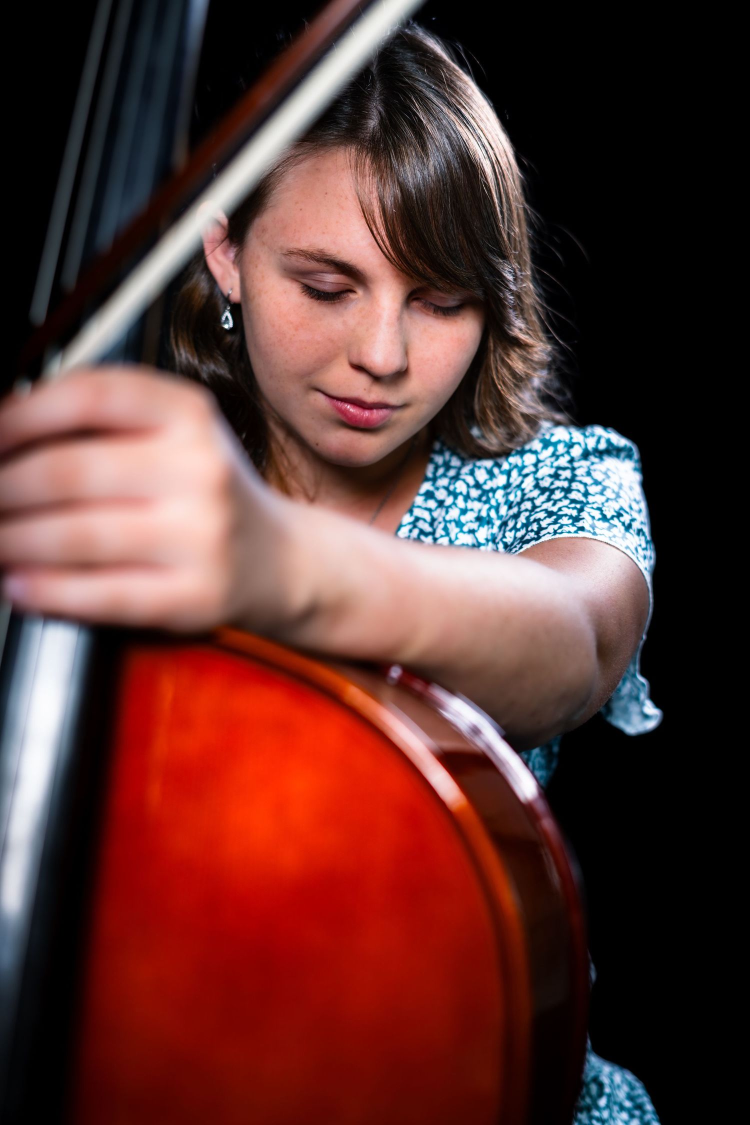Close-up shots of a musician playing cello with dramatic lighting against a dark background.