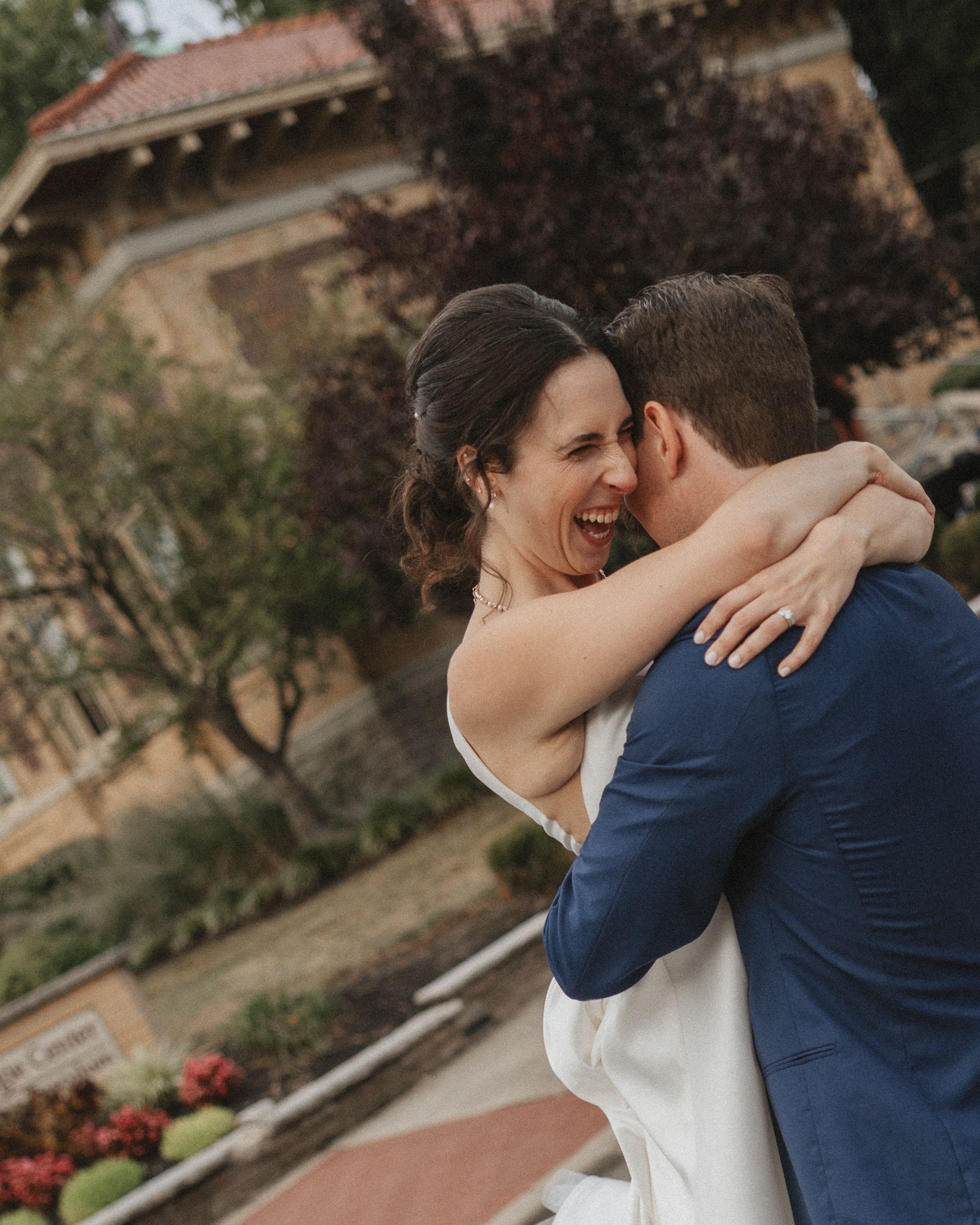 Newlywed couple shares intimate moments in a romantic outdoor garden setting with Spanish-style architecture.