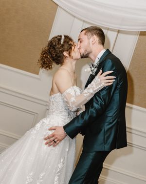 Couple in formal wedding attire sharing a romantic dance moment in an elegant room.