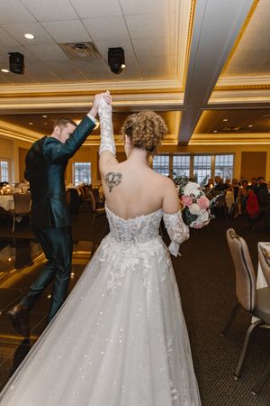Couple dancing at their wedding reception in a grand ballroom with elegant decor.