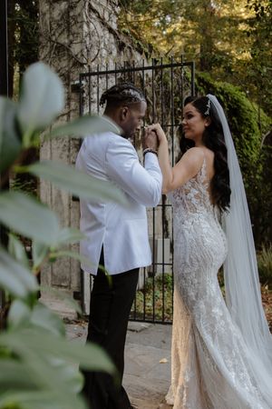 Romantic moment captured by stone wall and iron gate with natural foliage.