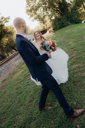 A wedding couple dances and twirls on a grassy hillside in a candid photo sequence.