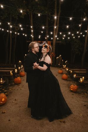 A romantic outdoor evening dance under string lights with pumpkins and candles creating a magical Halloween atmosphere.