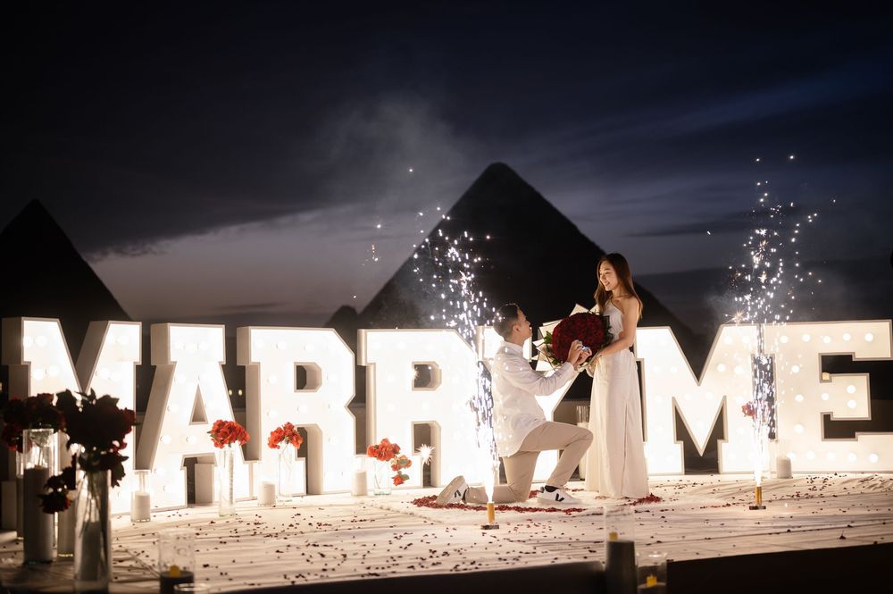 Illuminated white MARRY ME letters arranged on a beach at night with sparklers creating a romantic proposal scene.
