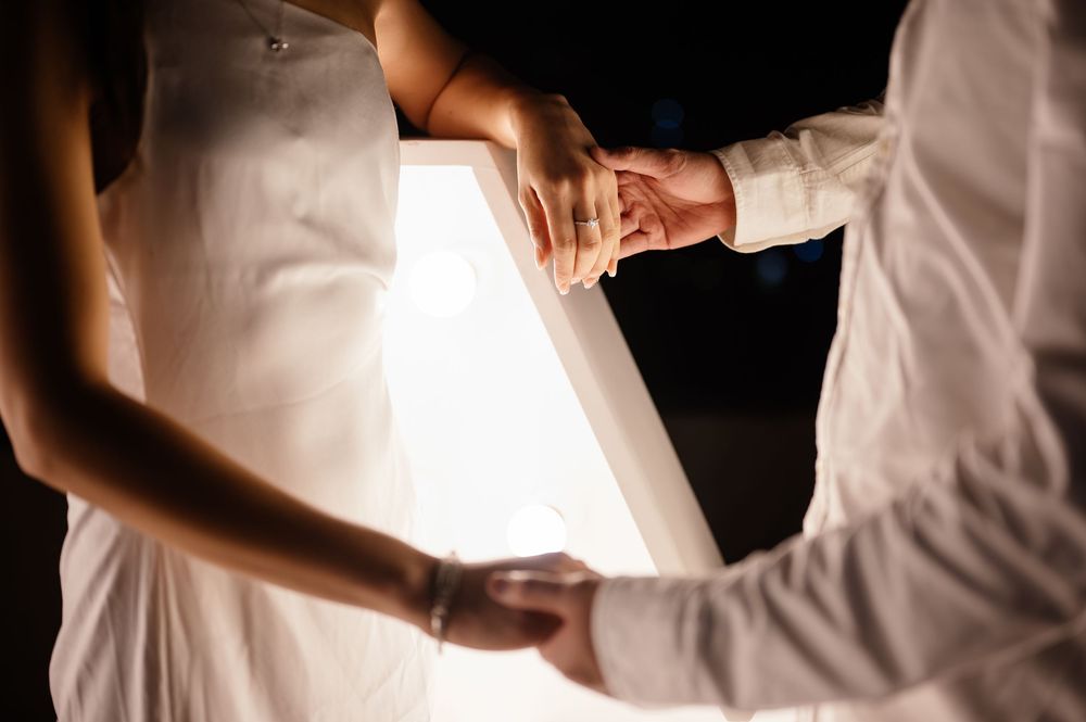 Two people dancing in elegant white wedding attire on a dance floor.