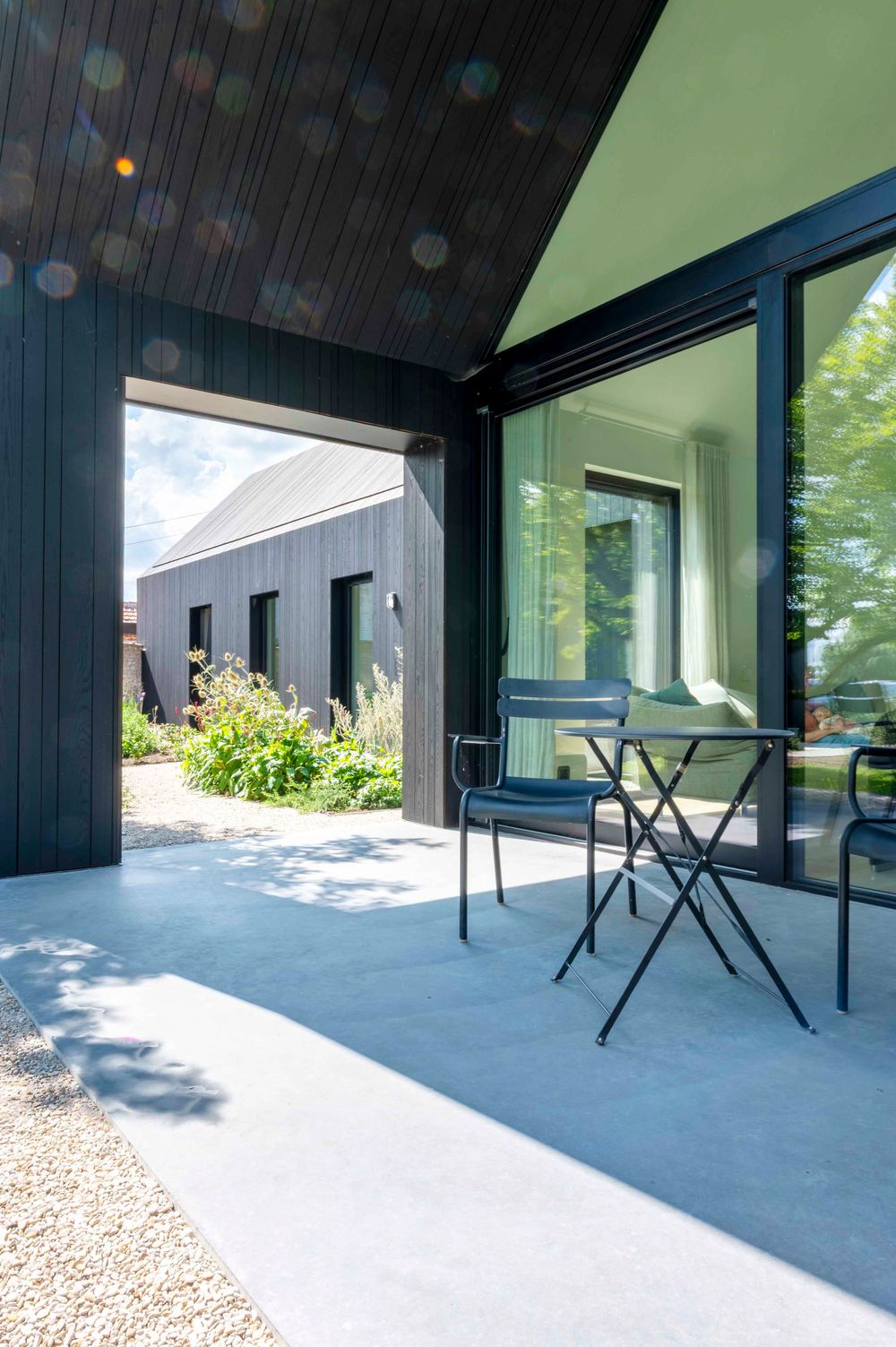 Covered outdoor terrace with modern black panels and folding furniture.
