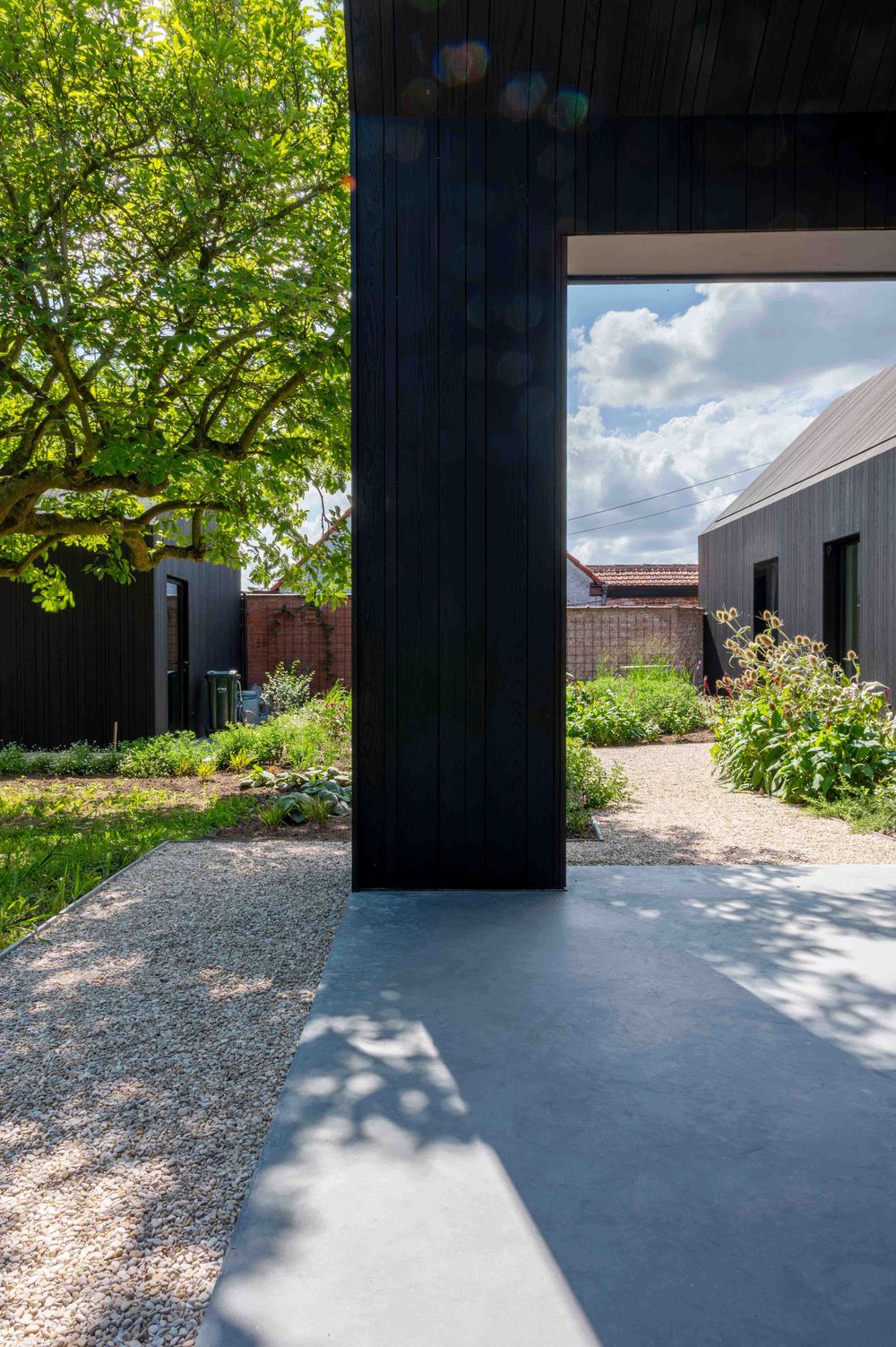 Contemporary building entrance with black exterior panels and landscaped garden path.