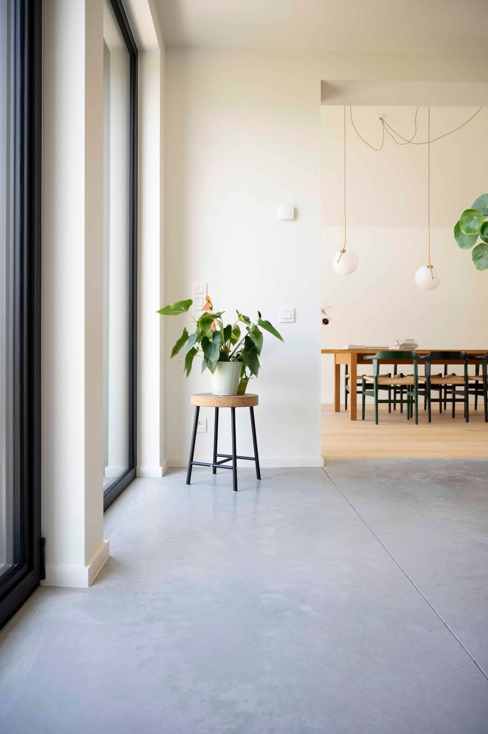 Modern open interieur. Betonnen keukenvloer in combinatie met een parketvloer in de eetruimte. Witte muren en minimalistisch meubilair.