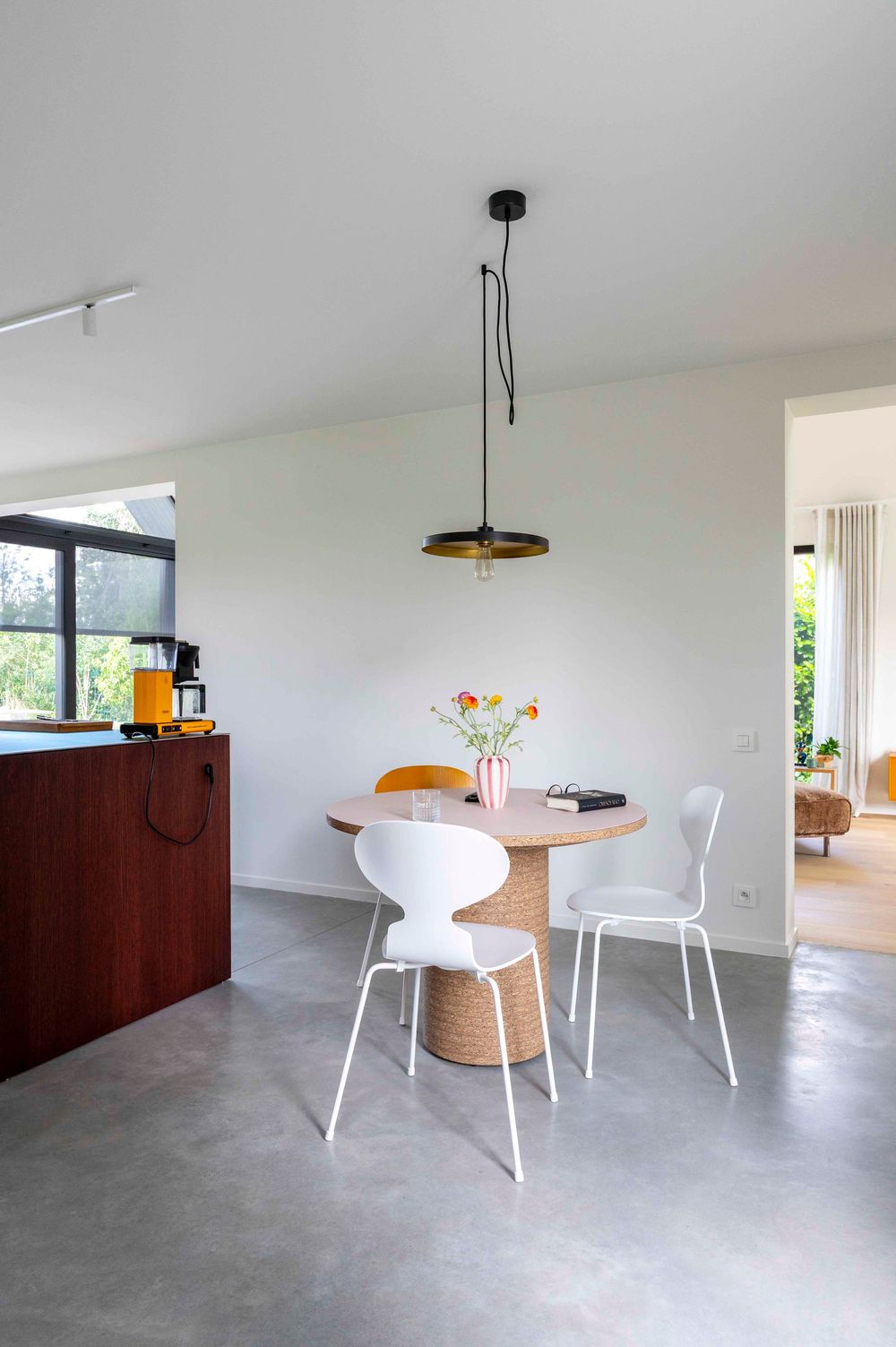 Contemporary minimalist dining area with white furniture and polished concrete floors.