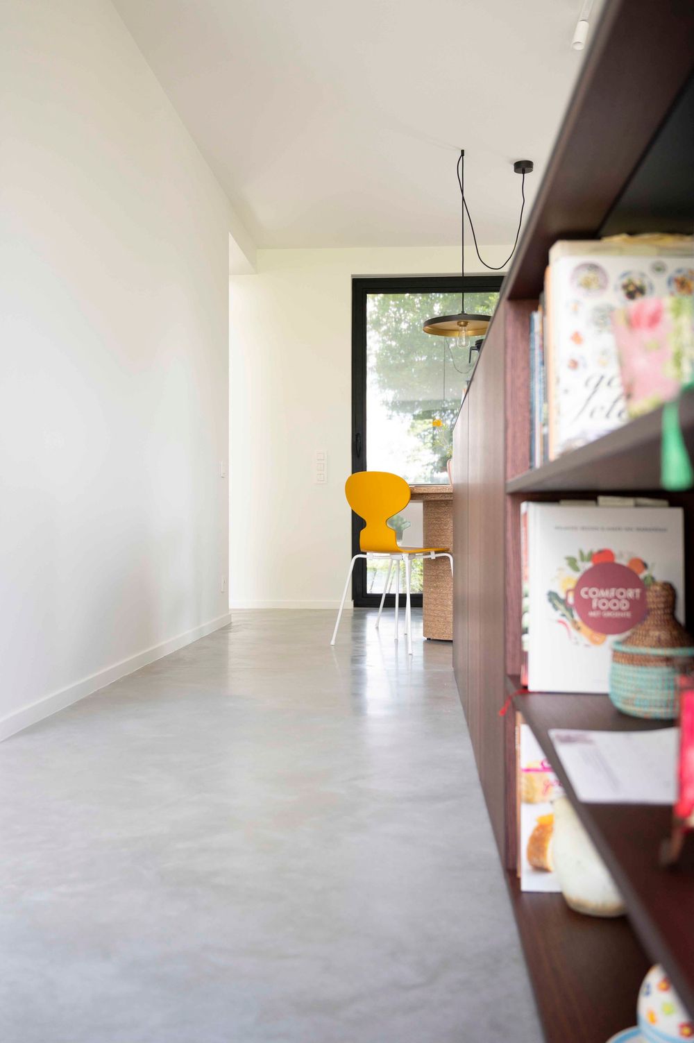Lange hal in een modern interieur met betonnen vloeren en ingebouwde houten kasten.