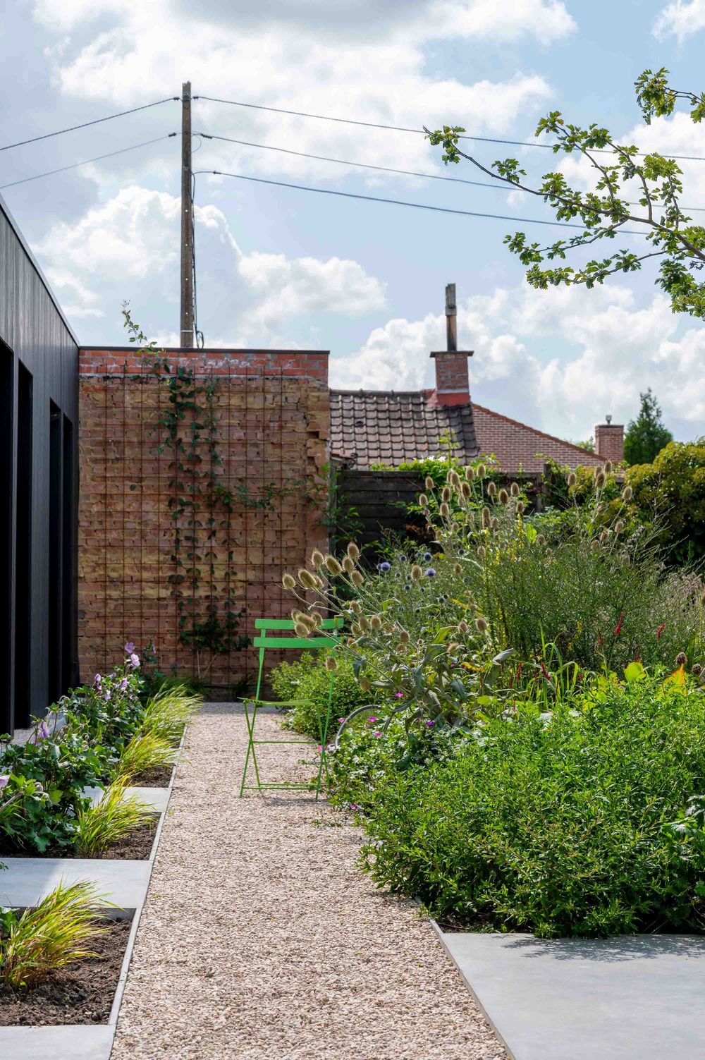 Landscaped gravel pathway leading through a modern garden with brick wall boundaries.