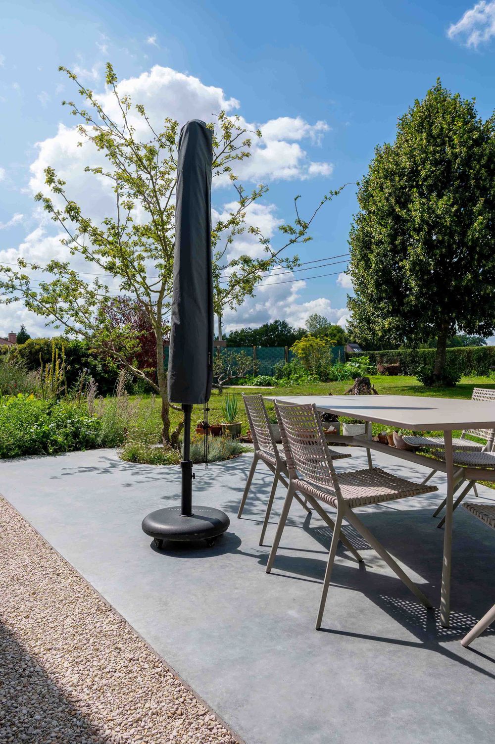 Outdoor patio area with modern furniture and umbrella set on polished concrete surface.