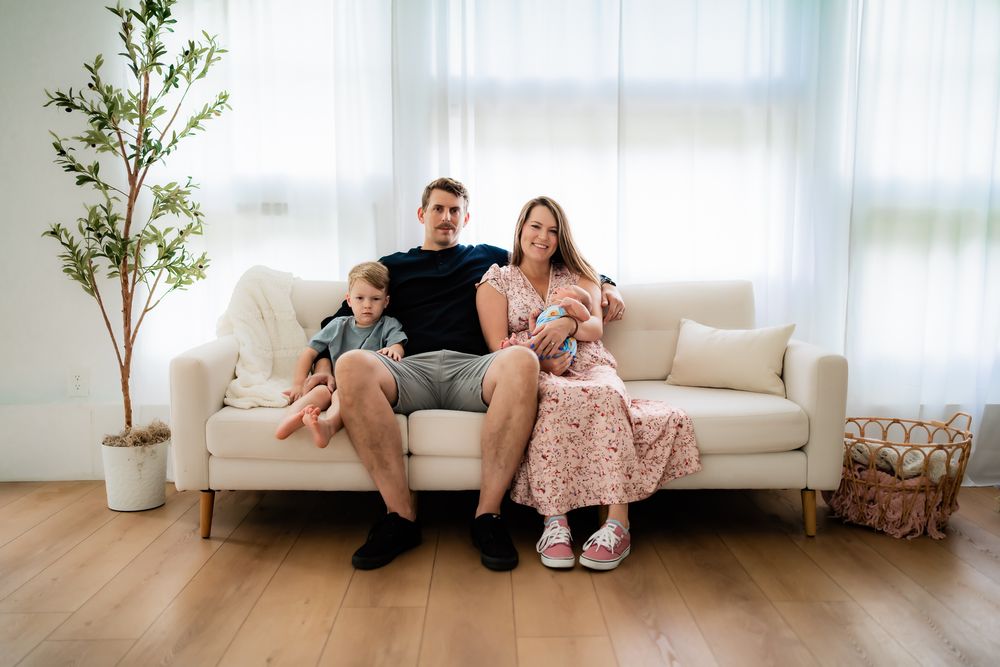 Family members relaxing on a white sofa in a bright modern living room with potted plants.